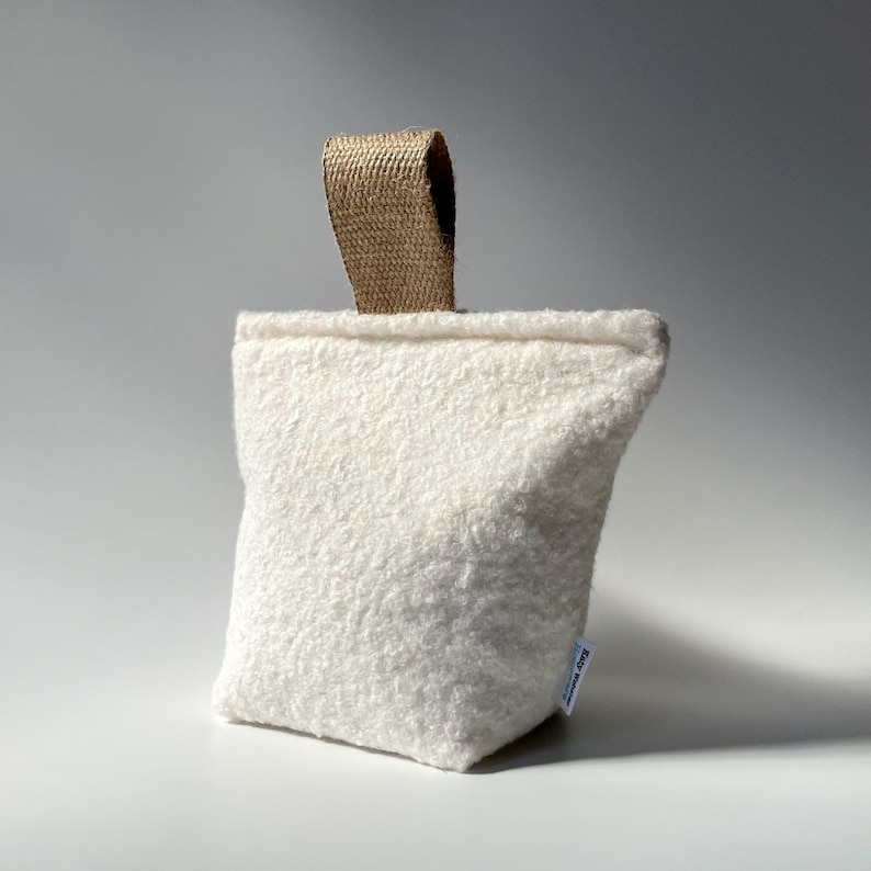 Ivory boucle fabric doorstop with jute handle.