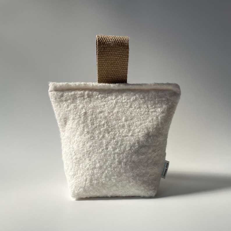 Ivory boucle fabric doorstop with jute handle.