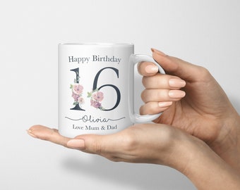 Może przedstawiać: Biały kubek ceramiczny z kwiatowym wzorem i liczbą 16. Na kubku nadrukowany jest tekst "Happy Birthday Olivia Love Mum & Dad".