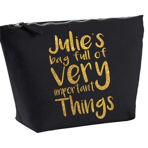 May include: Black canvas zippered pouch with gold glitter lettering that reads "Julie's bag full of very important things".