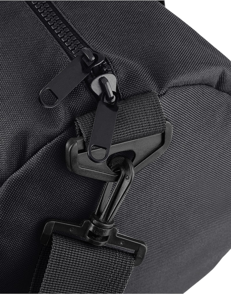 May include: Close-up of a black duffel bag with a zipper closure and a black strap with a clip. The bag is made of a durable, water-resistant material.