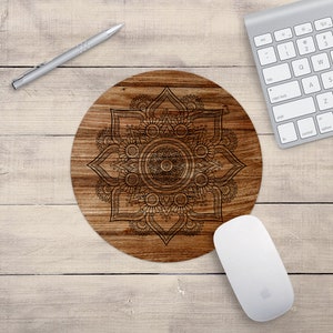 May include: A round wooden mouse pad with a black and white mandala design. The mandala is intricate and detailed, with a circular pattern of flowers and leaves.