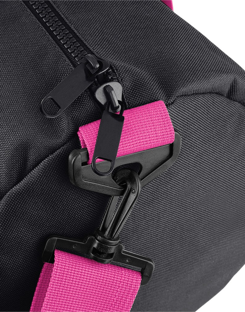 May include: Black duffel bag with a pink strap and a black zipper. The strap has a black plastic clasp.