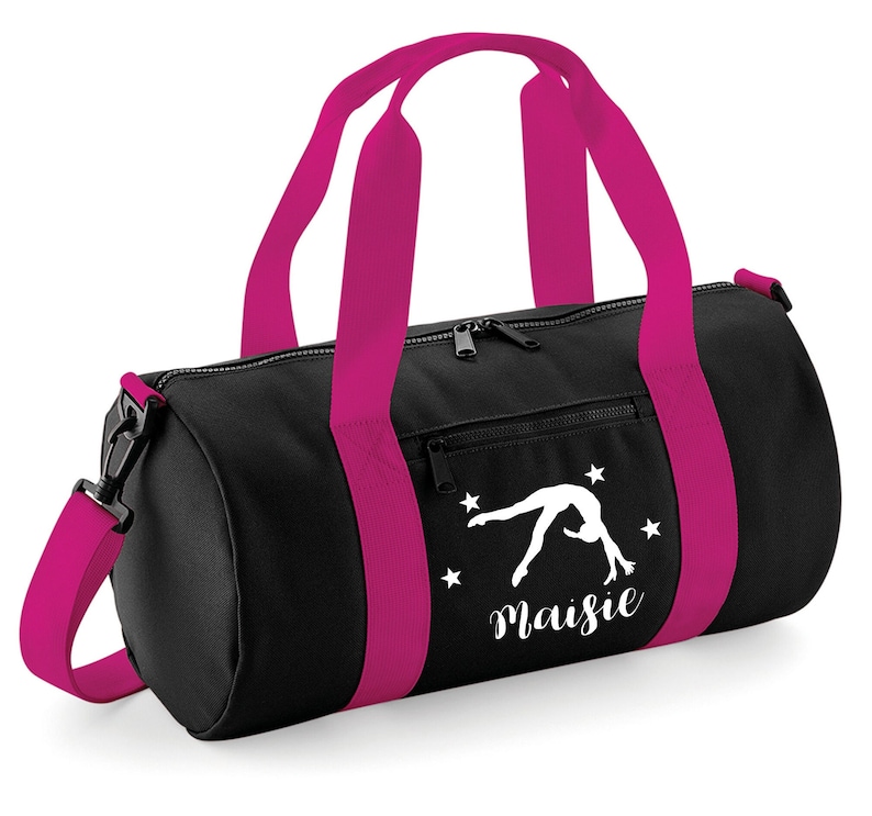 May include: Black gym bag with pink accents and a white silhouette of a gymnast doing a back handspring. The bag has a zippered pocket on the front and the name "Maisie" is printed below the gymnast.