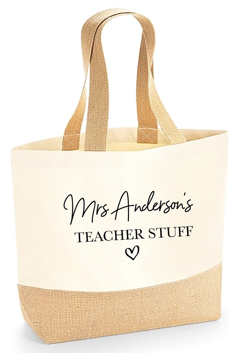 May include: A beige canvas tote bag with brown jute handles and a brown jute bottom. The bag has black text that says "Mrs. Anderson's Teacher Stuff" with a heart symbol.