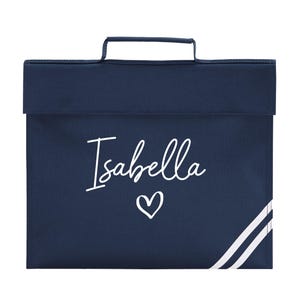 May include: A navy blue school bag with a handle and a flap. The name "Isabella" is written in white script, with a white heart below. White stripes decorate the lower right corner.