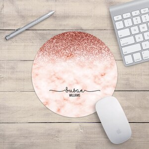 May include: Round pink and rose gold marble mouse pad with the name "Susan WILLIAMS" in black cursive writing.