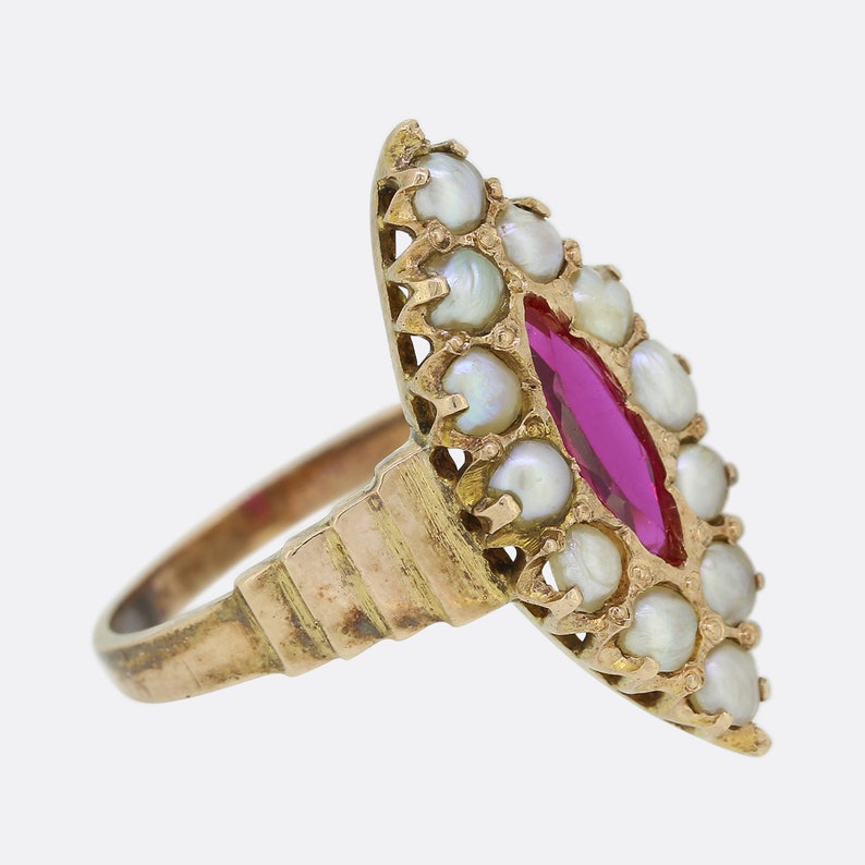 May include: A gold ring with a red gemstone surrounded by white pearls. The ring has a delicate, ornate design.