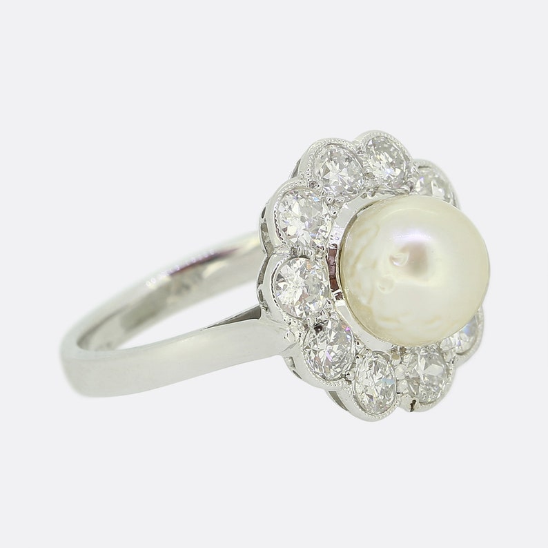 May include: A white pearl ring with a diamond halo setting. The ring is made of white gold and has a simple band.