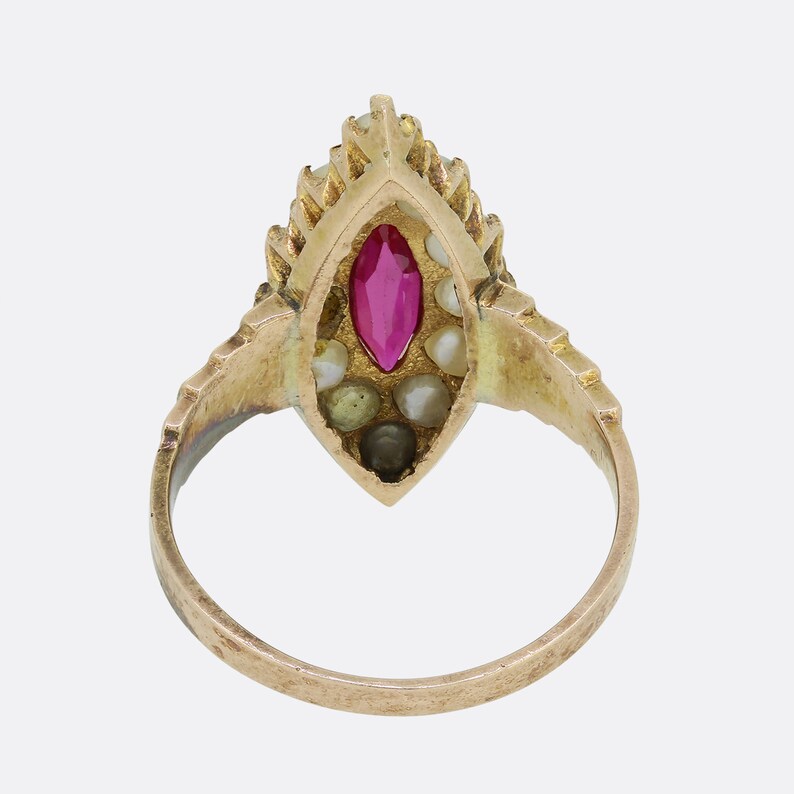 May include: A gold ring with a red gemstone surrounded by pearls. The ring is set in a marquise shape.