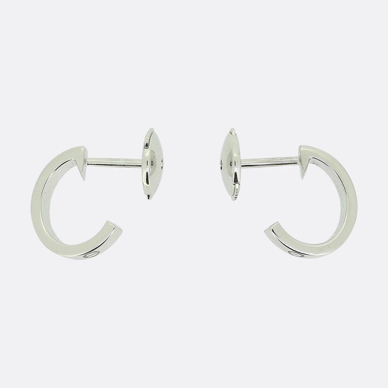 May include: A pair of silver hoop earrings with a small diamond on each hoop.