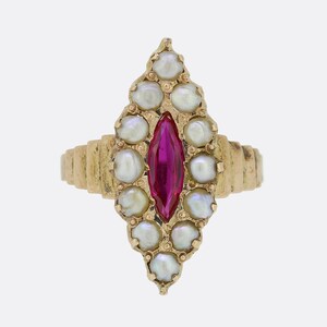 May include: A gold ring with a red gemstone surrounded by white pearls. The ring is set in a teardrop shape.