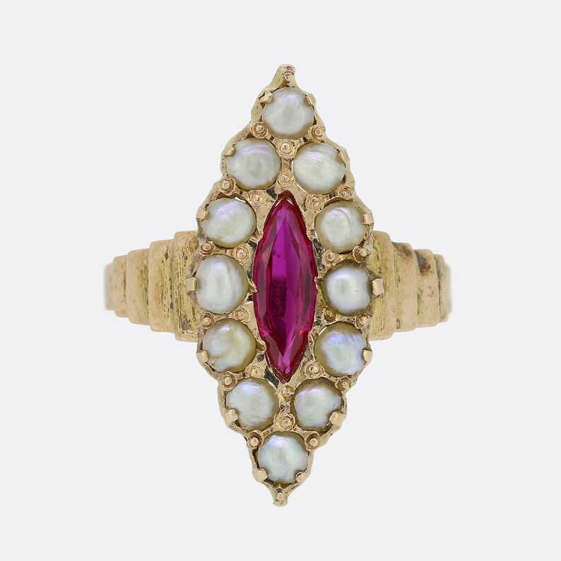 May include: A gold ring with a red gemstone surrounded by white pearls. The ring is set in a teardrop shape.