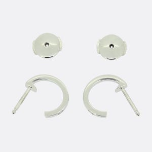 May include: A pair of silver hoop earrings with a small, round, silver post on each earring.