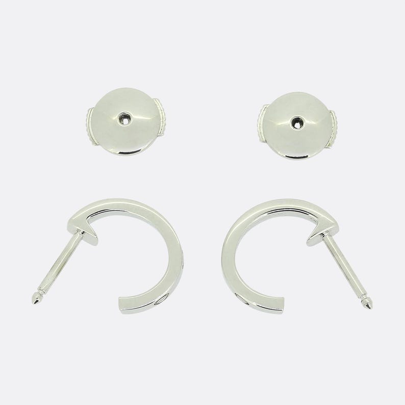 May include: A pair of silver hoop earrings with a small, round, silver post on each earring.