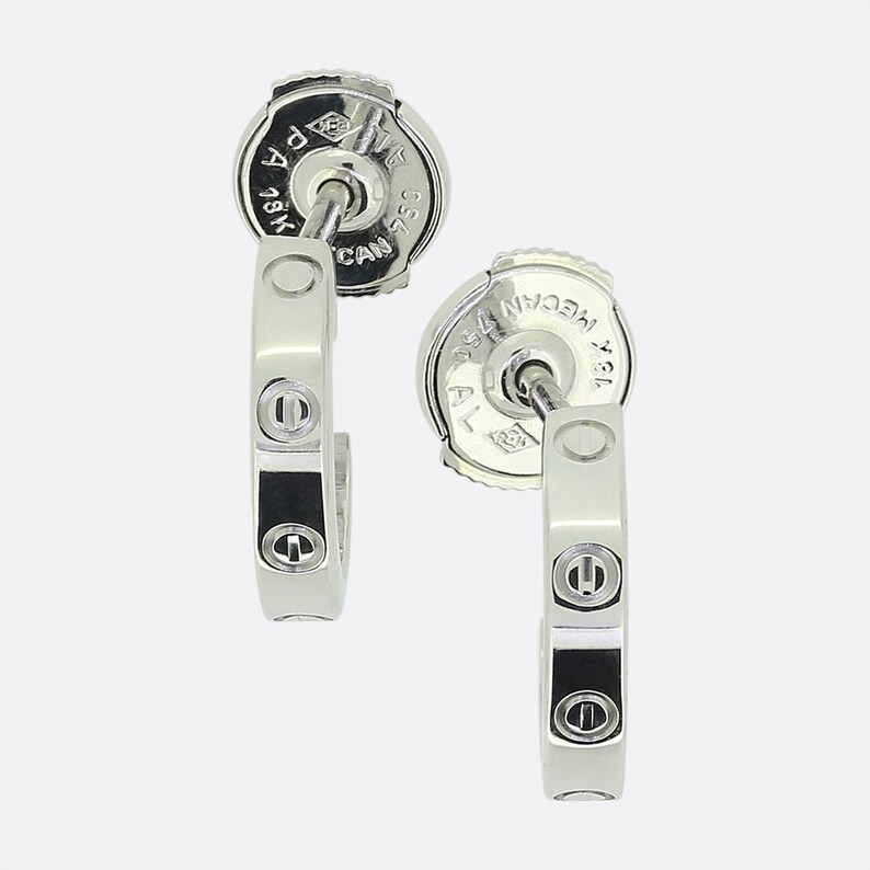 May include: Two silver hoop earrings with a row of four diamonds on each hoop. The back of the earrings are marked with '750' and '18K'.