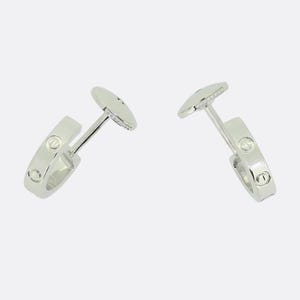 May include: Two silver hoop earrings with a row of small diamonds around the edge of each hoop.