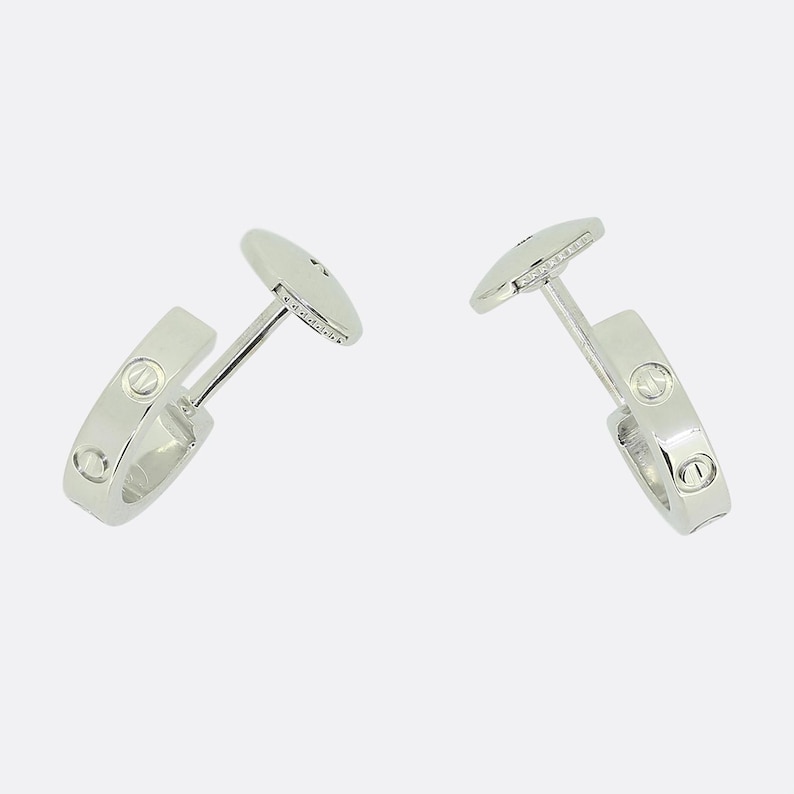 May include: Two silver hoop earrings with a row of small diamonds around the edge of each hoop.