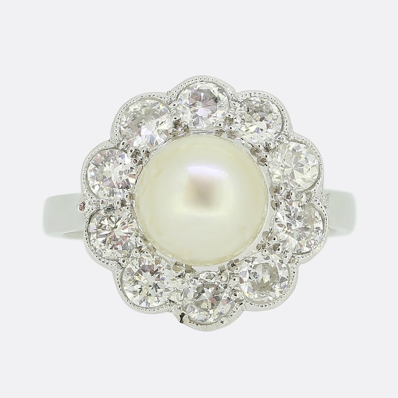 May include: A silver ring with a large white pearl surrounded by a halo of smaller diamonds.