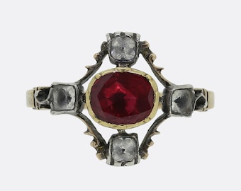 May include: A vintage ring with a red gemstone surrounded by four smaller clear gemstones. The ring is set in gold and silver.