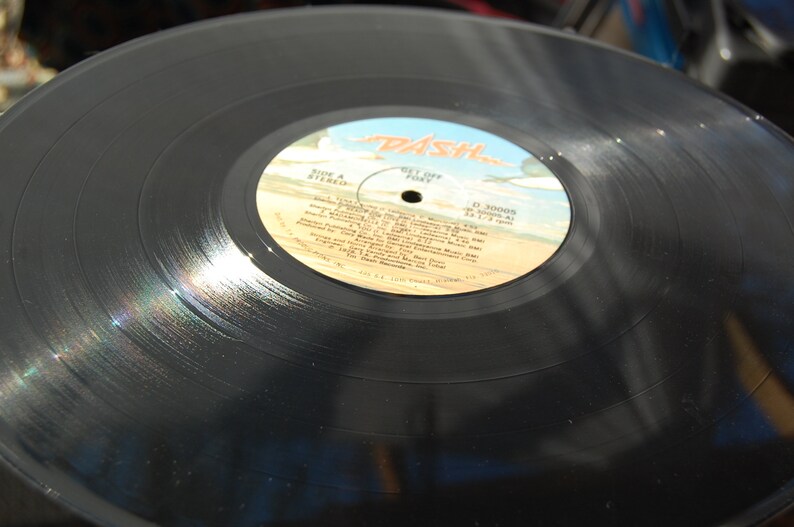 May include: Black vinyl record with a white label that says "Dash" in red letters. The label also includes the text "Side A Stereo" and "Get Off  Free" along with a list of song titles.