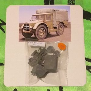 Puede incluir: Una bolsa de plástico que contiene un kit de maquetas de un camión Fiat SPA AS 37. El kit es a escala 1/32 e incluye una variedad de piezas, incluidas ruedas, neumáticos y una capota de lona. El kit está etiquetado como "FIAT SPA AS 37 Close."