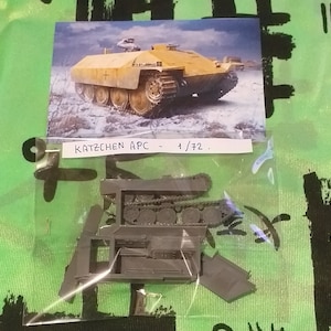 May include: A plastic model kit of a German armored personnel carrier, the 'Katzenchen APC', in 1/72 scale. The kit includes multiple pieces, including the chassis, tracks, and body of the vehicle.