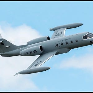 May include: A gray military jet aircraft in flight, featuring two engines mounted on the rear fuselage, wingtip fuel tanks, and a T-tail configuration. The fuselage displays the text T-22 and Fuerza Aerea Argentina with circular insignias.