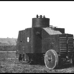 Puede incluir: Una fotografía en blanco y negro de un vehículo blindado antiguo que presenta una torreta cilíndrica alta, una rejilla de radiador montada en la parte delantera y grandes ruedas sólidas. El vehículo tiene una carrocería metálica remachada.