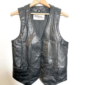 Peut inclure: Un gilet en cuir noir avec un col en V et deux poches. Le gilet porte une étiquette indiquant "Willowood, from all leather."