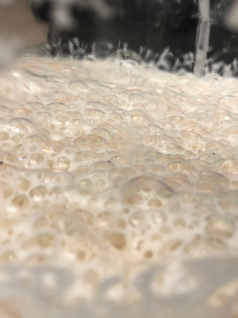 May include: Close-up of a white, foamy substance with small bubbles. The substance appears to be in a glass container.