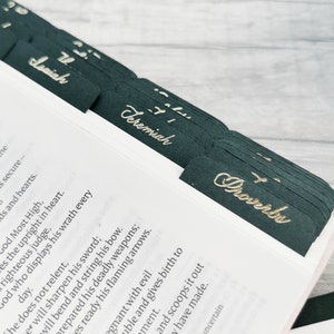 May include: Close-up of a black and gold book with tabs for the books of Isaiah, Jeremiah, and Proverbs. The tabs are made of black cardstock with gold lettering.