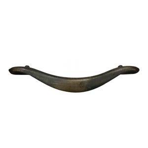 May include: A bronze-toned cabinet pull handle with a curved, wave-like design. The handle has a smooth, slightly textured surface and is mounted on a white background. The ends of the handle are rounded.