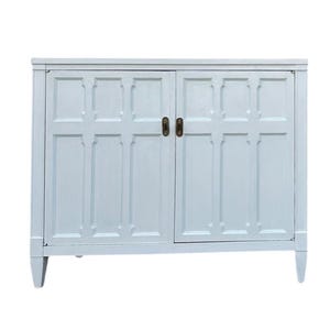 May include: A light blue cabinet with two doors and brass-colored handles. The cabinet has a rectangular shape with a decorative panel design on the doors and sides. The cabinet is painted in a matte finish and has four legs.