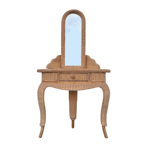May include: A light brown wicker vanity table featuring a tall, arched mirror attached to the back. The piece includes a central drawer with a small round knob, a flat tabletop surface, and three curved legs that provide a stable base structure.