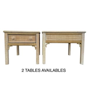 May include: Two light beige woven side tables. One table has a drawer with two decorative knobs. The tables have curved legs and a woven design. The text "2 TABLES AVAILABLES" is at the bottom of the image.
