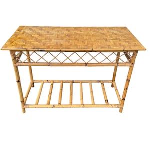 May include: A rectangular bamboo coffee table with a woven top and a lower shelf. The table has a natural, light brown color and features a diamond-patterned design on the sides. The table measures approximately 48 inches long, 24 inches wide, and 18 inches high.