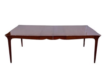 May include: A dark wood dining table with a rectangular top and curved legs. The table has a leaf that extends the length of the table.