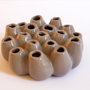 Könnte beinhalten: Eine graue Keramik-Blumenvase mit mehreren Öffnungen für Blumen. Die Vase hat die Form eines Büschels abgerundeter Knospen.