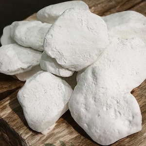 May include: A cluster of white chalk rocks with an irregular shape, placed on a weathered, brown wooden surface. The rocks have a textured finish. The text "UACHALKS.COM" is visible at the bottom of the image.