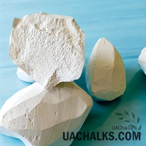 May include: White chalk rocks, irregularly shaped, on a blue background. The rocks are stacked on top of each other. The text "UACHALKS.COM" is visible in the lower right corner of the image.