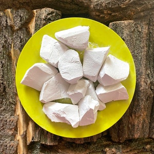 May include: A yellow plate with white chalk pieces on it. The plate is on a wooden surface.