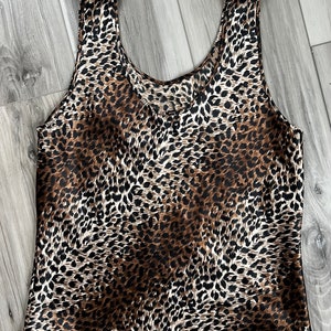 May include: A brown and black leopard print tank top made of satin.