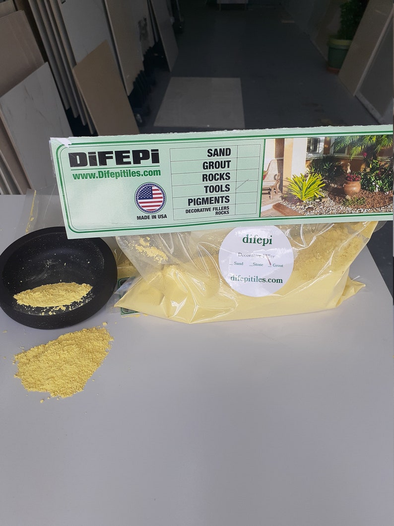 May include: A yellow bag of decorative filler for landscaping and crafts. The bag is labeled "difepi" and "www.difepitiles.com". The label also lists the products offered by the company: sand, grout, rocks, tools, pigments, and decorative fillers.