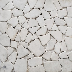May include: A close-up of a white stone mosaic wall. The stones are irregular in shape and size, creating a textured surface.