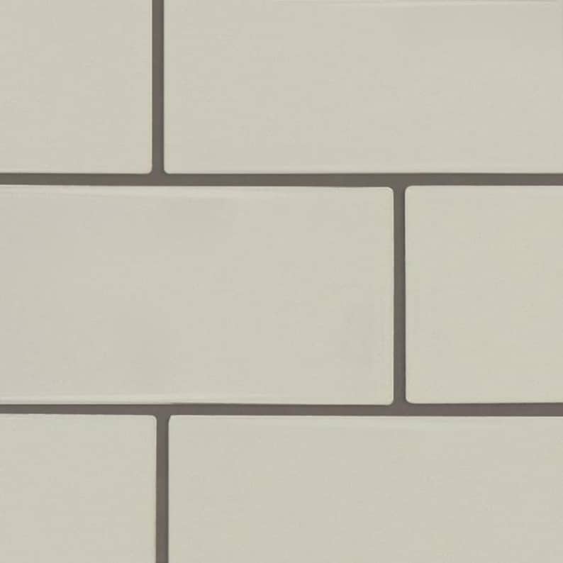 May include: A close-up of a white tiled wall with grey grout lines. The tiles are arranged in a staggered pattern.