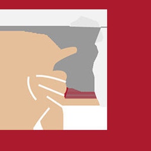 May include: A close-up of a hand holding a red and white striped fabric with a gray background.