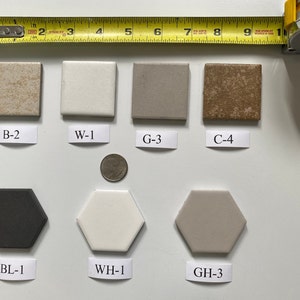 Puede incluir: Un conjunto de 8 azulejos de cerámica en varios colores y formas. Los azulejos están dispuestos en dos filas. La fila superior tiene cuatro azulejos cuadrados etiquetados como B-2, W-1, G-3 y C-4. La fila inferior tiene tres azulejos hexagonales etiquetados como BL-1, WH-1 y GH-3.