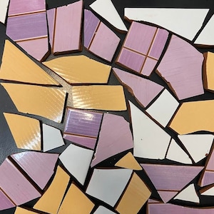 Puede incluir: Una colección de azulejos de cerámica rotos en varios tonos de morado, amarillo y blanco. Los azulejos están dispuestos en un patrón aleatorio sobre una superficie negra.