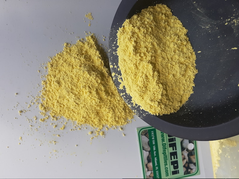 May include: Yellow powder in a black bowl and on a white surface. The powder is a food ingredient called "Difeptiles". The text on the label reads "Difeptiles.com www.Difeptiles.com 19170 SW 106 Ave. Miami, FL 33157"